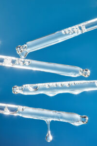 Transparent serum droppers floating on a clean blue background