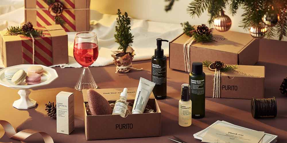 푸리토 스킨케어 제품들과 포장 박스가 따뜻한 홀리데이 분위기 속에 연출된 이미지 Purito skincare products arranged in a warm, festive holiday scene
