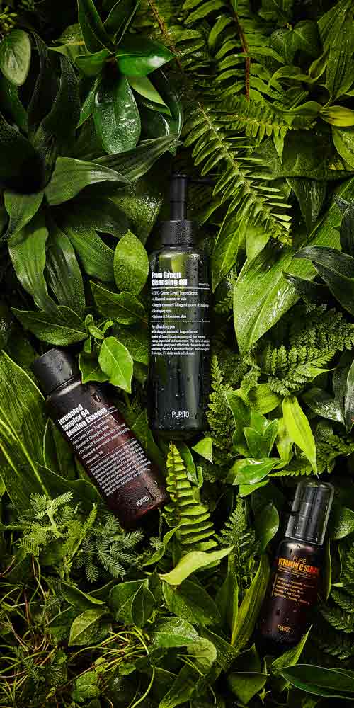 푸리토 클렌징 오일, 에센스, 세럼이 울창한 잎 배경에 놓인 이미지 Purito cleansing oil, essence, and serum placed against a lush green leaf background