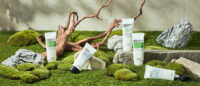 푸리토 선케어 제품이 이끼와 암석, 고사리 배경에 놓인 이미지 Purito sun protection skincare products displayed among moss and rocks