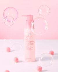 Pink cleanser bottle with floating bubbles and puff balls