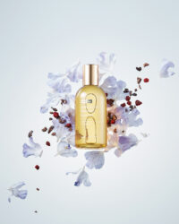 Essence bottle with floral and botanical elements on soft background