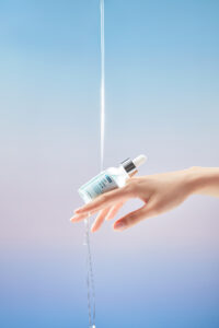 Hand holding ByWishtrend Hydra Ampoule with water stream