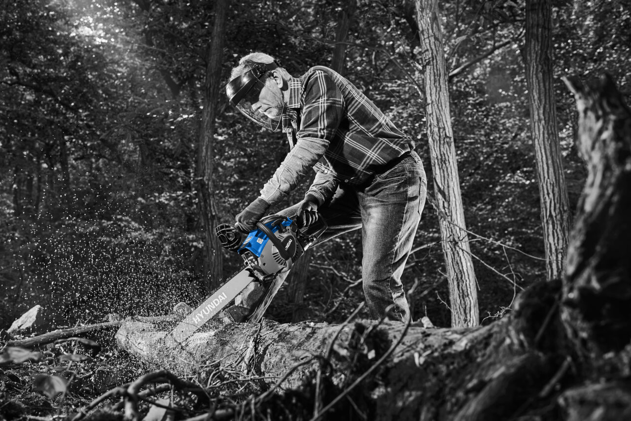 숲속에서 전기톱으로 벌목하는 장면을 연출한 포트폴리오 사진 Portfolio photo featuring a man using a chainsaw in a realistic forest setting