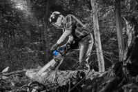 숲속에서 전기톱으로 벌목하는 장면을 연출한 포트폴리오 사진 Portfolio photo featuring a man using a chainsaw in a realistic forest setting