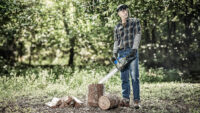 숲속에서 전기톱을 들고 있는 모델 이미지 Photo of a man standing outdoors holding a chainsaw