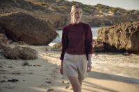 해변에서 버건디 가디건과 베이지 쇼츠를 착용한 모델 Model wearing burgundy cardigan and beige shorts on the beach
