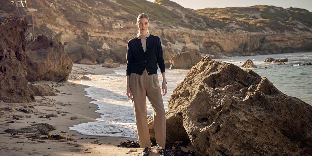 바닷가 절벽을 배경으로 선 채 바람을 맞고 있는 여성 모델의 전신 컷 A full-body portrait of a female model standing by a seaside cliff under sunlight