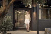 테라스 앞에서 베이지 상의와 아이보리 쇼츠를 입은 모델 Model wearing beige top and ivory shorts in front of a modern terrace building