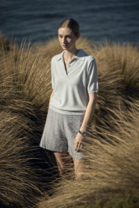 억새풀 사이에서 자연광을 받는 모델의 측면 초상 이미지 A model standing in tall dry grass near the sea wearing Elune Mode SS look