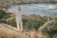 해안 절벽 위 베이지 니트 상의와 팬츠를 착용한 여성 모델 Female model in beige knit top and ivory trousers at a cliffside