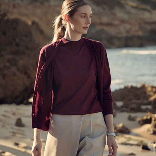 해변에서 버건디 상의와 아이보리 쇼츠를 착용한 여성 모델 Female model in burgundy top and ivory shorts at the beach