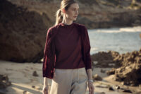 해변에서 버건디 상의와 아이보리 쇼츠를 착용한 여성 모델 Female model in burgundy top and ivory shorts at the beach