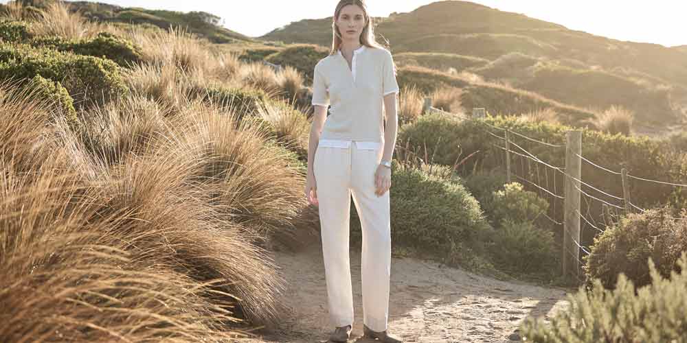 부드러운 여름 빛 아래 크림 톤 팬츠를 입은 여성 모델 Female model wearing cream trousers and minimal top in golden hour
