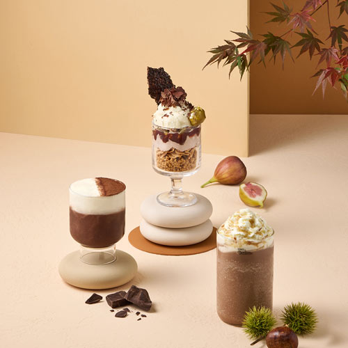 Three Godiva chocolate drinks with figs and chestnuts on beige background