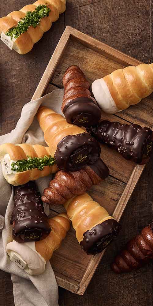 Assorted chocolate and cream-filled bread cones arranged on a wooden tray