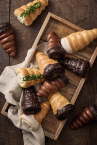 Assorted chocolate and cream-filled bread cones arranged on a wooden tray