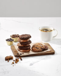 Stack of chocolate chip cookies with a coffee cup on marble table