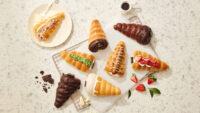 Flatlay of assorted Godiva cone breads with props like coffee, fruit, and crumbs