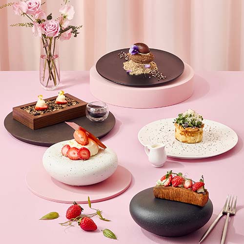 Assorted Godiva desserts arranged on various plates over a pink table setting