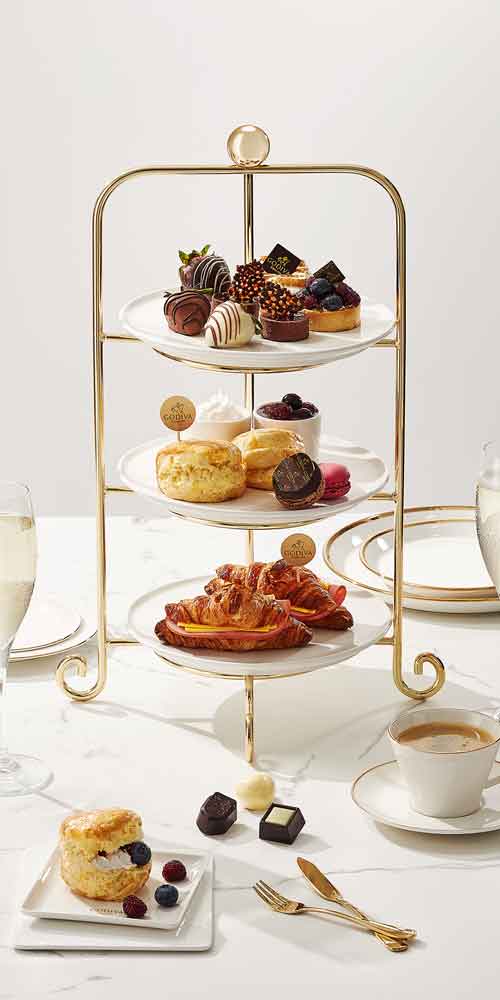 Elegant studio photo of a four-tier Godiva dessert set with drinks