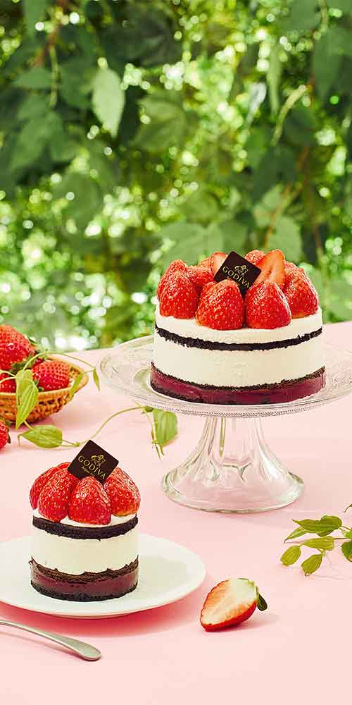 Godiva strawberry layer cakes styled on a pink table in a green outdoor setting