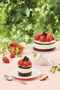 Godiva strawberry layer cakes styled on a pink table in a green outdoor setting