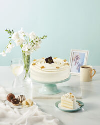 White cream cake with golden toppings on a pastel blue table