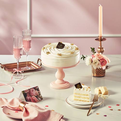 White cream cake with floral styling and pink champagne