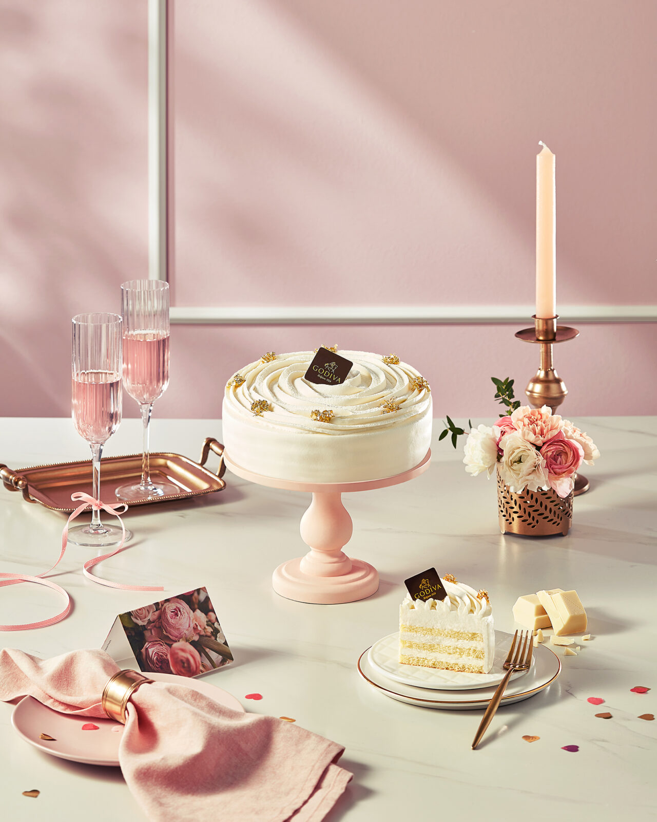 White cream cake with floral styling and pink champagne