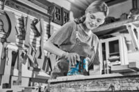 공방에서 샌더를 사용하는 여성 A woman cutting wood with a sander in a workshop