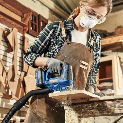 공방에서 목재를 자르고 있는 여성 A woman cutting wood with an electric jigsaw in a workshop