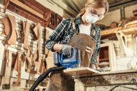 공방에서 목재를 자르고 있는 여성 A woman cutting wood with an electric jigsaw in a workshop