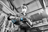 목재를 연마하는 여성, 마스크와 고글 착용 Female worker sanding wood with grinder, wearing safety gear