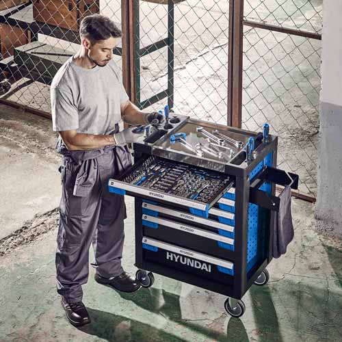 툴카트 옆에서 장비를 정리하는 정비사 Mechanic organizing equipment by a tool cart in workshop