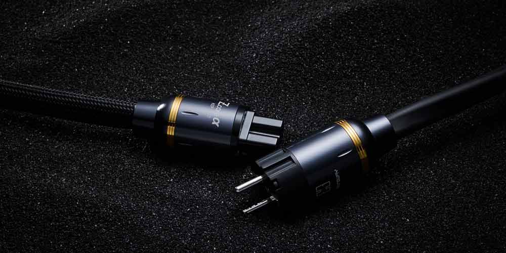 검은 모래 위에 놓인 헤밍웨이 전원 케이블 Hemingway high-end power cable on textured black sand