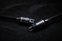 검은 모래 위에 놓인 헤밍웨이 전원 케이블 Hemingway high-end power cable on textured black sand