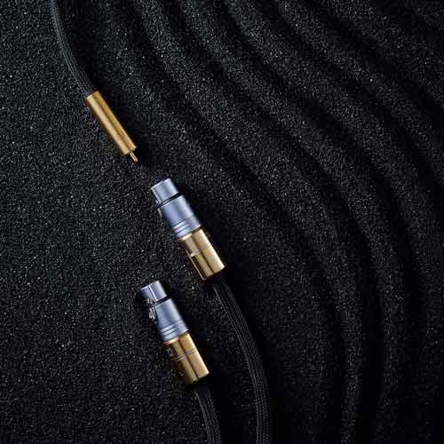 XLR 및 RCA 단자가 연결된 오디오 케이블 XLR and RCA audio cables on black textured sand