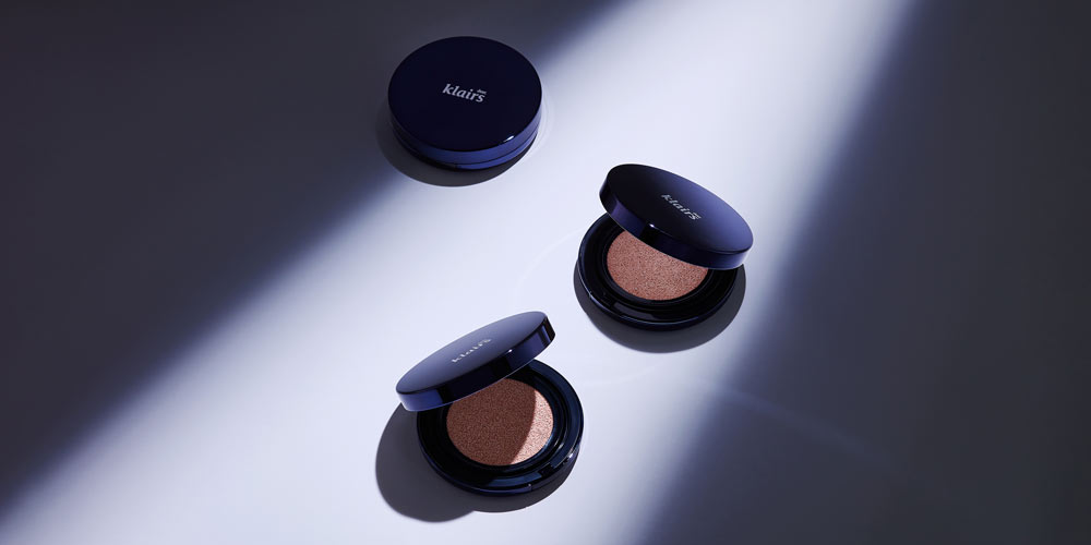 클레어스 쿠션 제품이 드라마틱한 조명 아래 놓인 모습 Klairs cushion compacts under dramatic spotlight