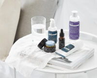 사이드테이블 위에 구성된 Klairs 스킨케어 제품들과 크림 텍스처 표현 이미지 Styled still life of Klairs skincare products on a bedside table