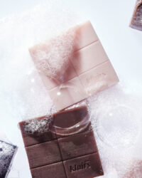 클레어스 비누 두 가지 색상이 거품 위에 놓인 모습 Two Klairs facial soaps placed on a bed of white bubbles