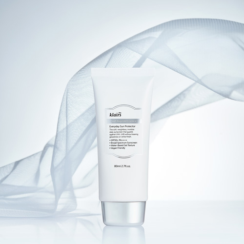 부드러운 천과 함께 연출된 클레어스 선크림 제품 이미지 Klairs sunscreen tube staged with flowing fabric and soft lighting