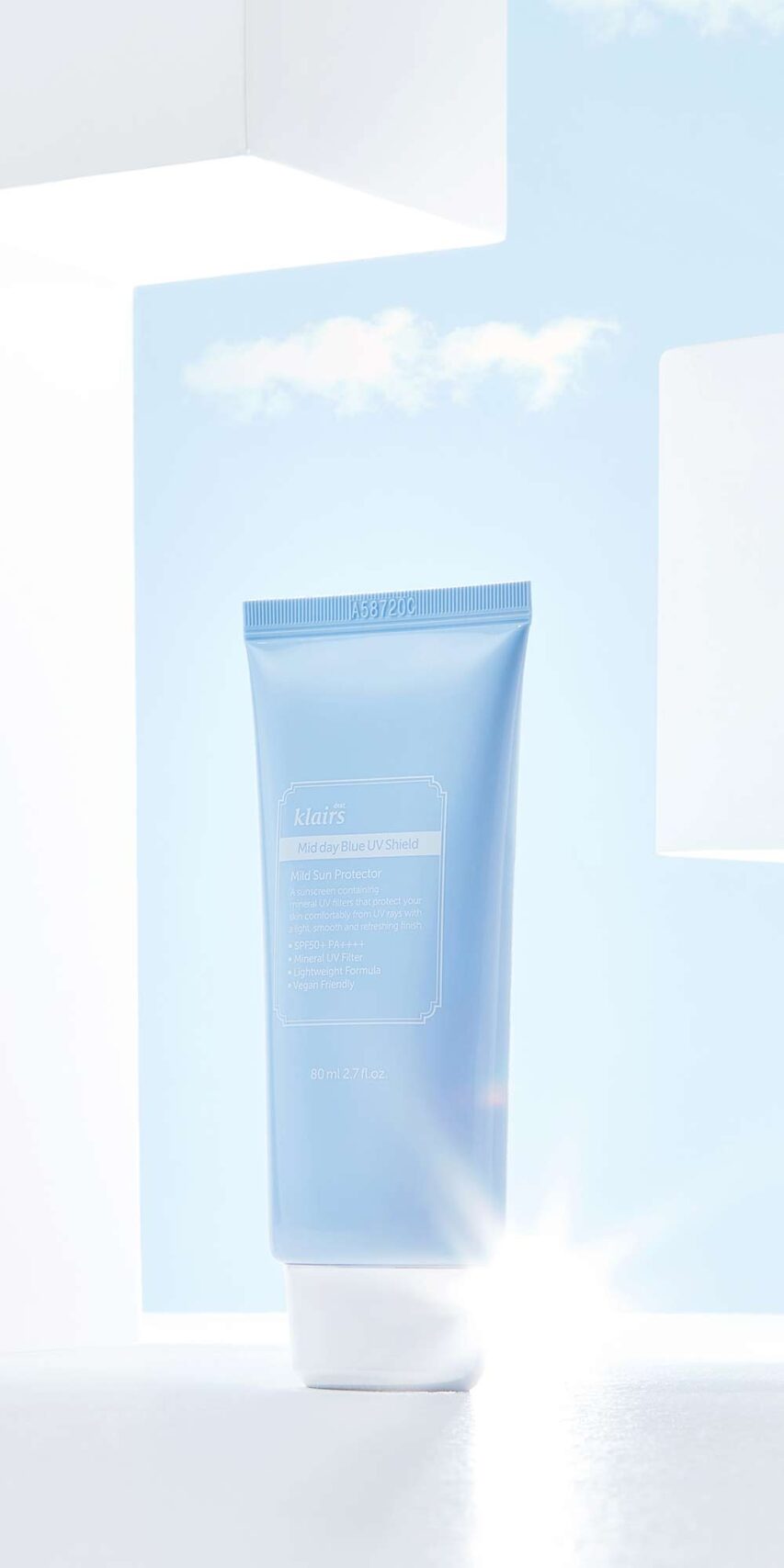 파란 하늘 배경 안에 단독 배치된 Klairs 선크림 제품 이미지 Still life of Klairs blue sunscreen product with clean sky background and white framing