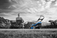 벤치에 앉아 잔디깎이를 바라보는 남성 모델의 흑백+컬러 연출 사진 Photo of a man sitting on a bench facing a lawn mower in black and white with color highlight