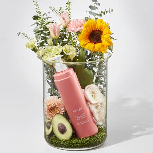 유리병 안에 꽃과 아보카도, 오제끄 바디로션이 함께 구성된 이미지 Floral arrangement in glass vase with avocado and Oseque body lotion bottle