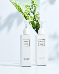 오제끄 클렌저 2종이 화사한 자연광과 초록 식물 그림자 배경에서 연출된 이미지 Two Oseque Cyber Shine Cleansers arranged on white surface with leafy shadows