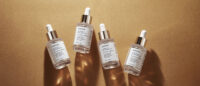 빛과 그림자가 강조된 바닥 위에 배치된 오제끄 하이드레이팅 스킨 퍼펙터 앰플 4개 Four Oseque Hydrating Skin Perfector Ampoules placed on warm-toned textured surface