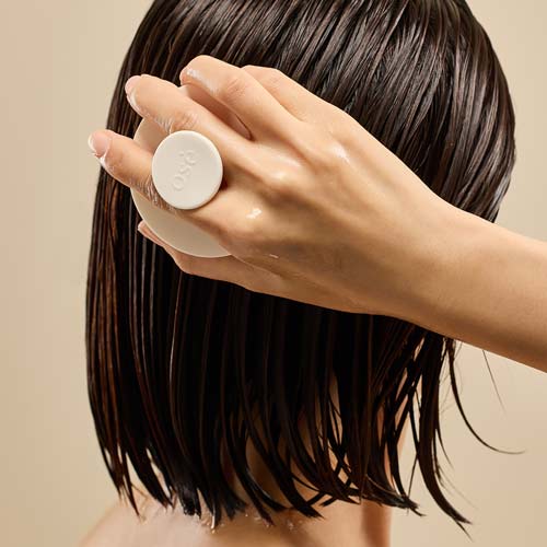 젖은 머리에 오제끄 천연비누를 사용하는 장면 A hand using Oseque white soap on wet hair from behind