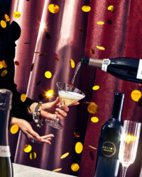 금빛 장식이 흩날리는 가운데, 와인을 따라 붓고 잔을 받는 순간의 연출 이미지 A festive image of a wine being poured into a glass, surrounded by golden confetti and red velvet curtains
