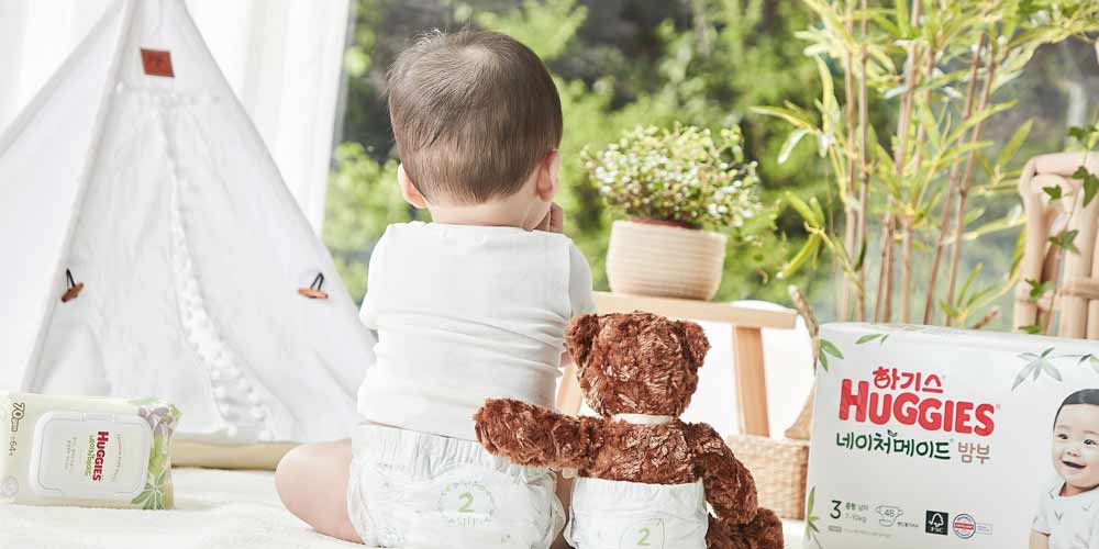 Baby with Teddy Bear and Huggies Diaper Pack in Cozy Room